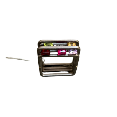 Silver ring with colored stones on a concrete surface