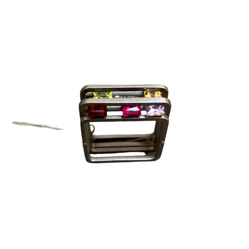 Silver ring with colored stones on a concrete surface
