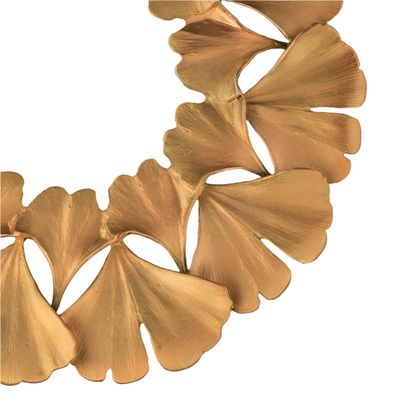 Close-up of a gold trivet with leaf-like pendants on a black background