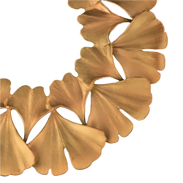 Close-up of a gold trivet with leaf-like pendants on a black background